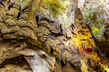 Flowstone (Petrification waterfalls, draperies) in Prometheus Cave Natural Monument, ceiling with stalactites and stalagmites, colorful illuminated rock formations.