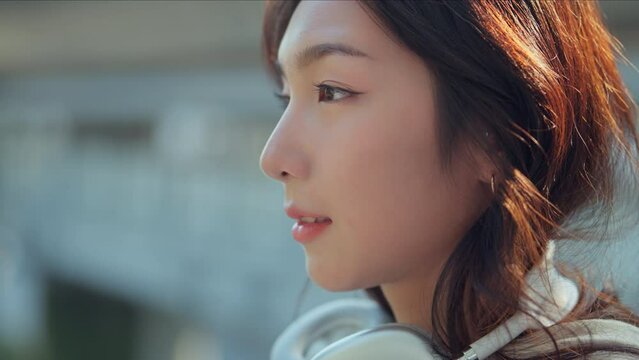 Close up - Attractive young asian woman opens his black eyes and smiling on a blurred background city, Enjoy moment of peace, Happy young woman enjoys life