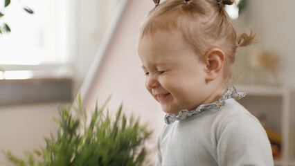 Little cute baby girl smiling with closed eyes. The child sits on his mother's lap. Mom tickles the...