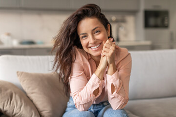 Woman with bright smile resting on sofa at home