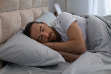 European man sleeping peacefully in cozy bed at home