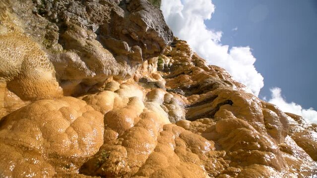 Carbonate mineral water flows over the yellow surface of travertine. Natural background or texture