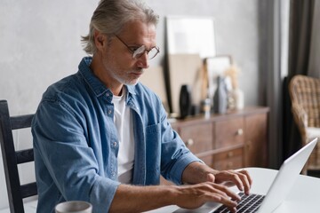 Middle-aged man working from home-office on laptop.