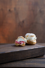 Profiterole cake with berry sauce cut into a section on a wooden table