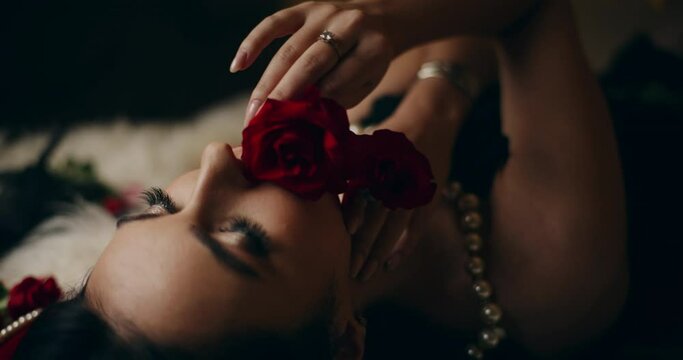 Sensual woman smelling and touching face with roses