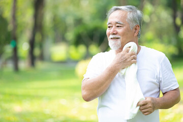 Naklejka na ściany i meble asian senior man wiping his face with white towel after workout in the park