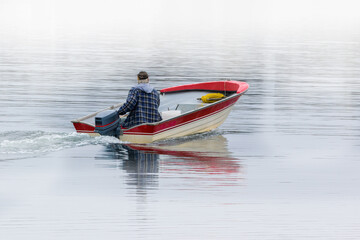 Fisherman leaving in a boat on water in foggy weather