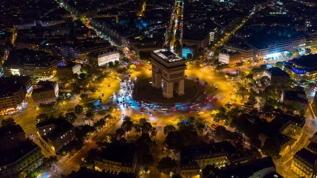 PARIS, FRANCE - FEBRUARY 20, 2024: Aerial drone timelapse motion hyperlapse view of the Arc de Triomphe (Triumphal Arch of the Star) with traffic on circle road. Famous monument at night from above.