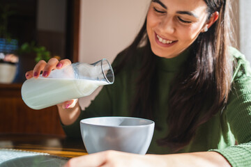 A young woman eating corn flakes for breakfast in the morning in her apartment	