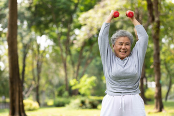 asian elderly woman exercising and lifting dumbbells in the park - obrazy, fototapety, plakaty