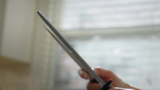 Closeup shot of an Asian woman sharpening a knife
