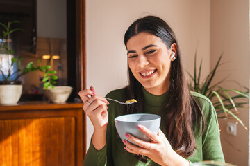 A young woman eating corn flakes for breakfast in the morning in her apartment	