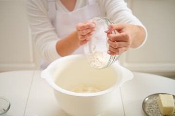 A woman pours flour into a bowl for making pie dough. Process of cooking pecan pie in home kitchen for American Thanksgiving Day.