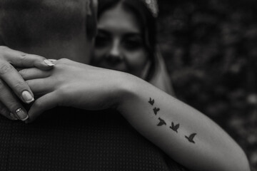 bride hugs groom arm tattoo in the form of flying birds swallows