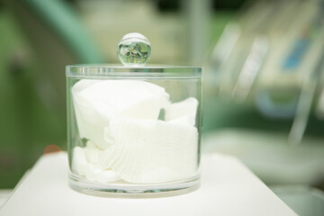 Clear glass container with gauze with background of a dental office with space for text