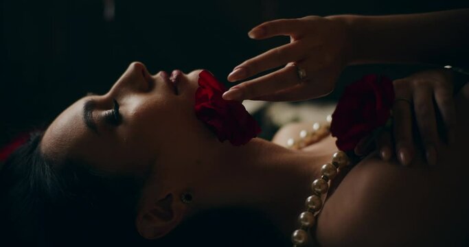 Seductive woman touching face and body with rose