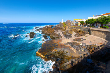Naklejka premium The volcanic rock coastline and blue turquoise water at the historic town of Garachico, Spain, on the Northern coast of Tenerife, an island in the Atlantic Ocean and part of the Canary Islands.