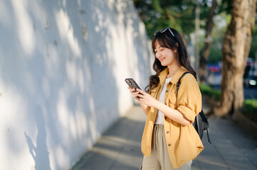 Traveler young asian woman in her 30s explores Bangkok with her smartphone. Capture the beauty and...