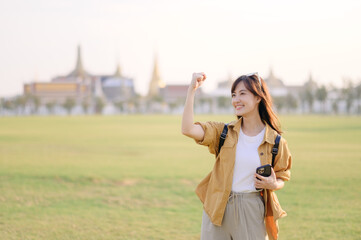 Traveler asian woman in her 30s navigates the bustling grounds of Wat Pra Kaew. Technology helps...