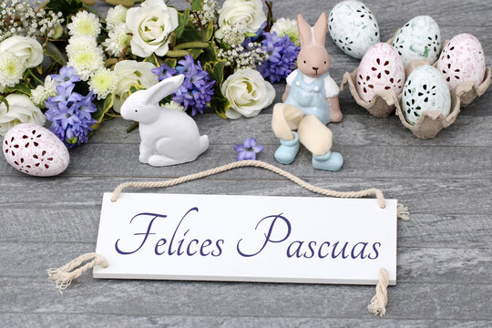 El texto Felices Pascuas escrito en un cartel con adornos y flores de Pascua.	