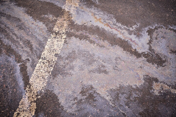 Oil, gasoline, or oil spill on wet asphalt with a parking lot and a dividing line.