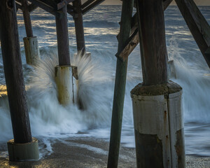 Waves crashing under the pier at sunrise