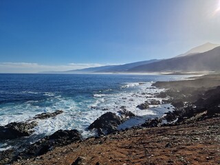 Rocky shore and natural pools of Tenerife coast, with white rolling waves of the sea breaking