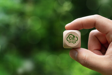 Reduce carbon dioxide emissions to limit climate change and global warming. Low greenhouse gas levels help reduce carbon emissions. Zero carbon and hand holding wooden block with green co2 icon - obrazy, fototapety, plakaty
