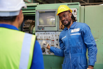 African foreman or technician training and teaching how to use machine control with coworker in the factory