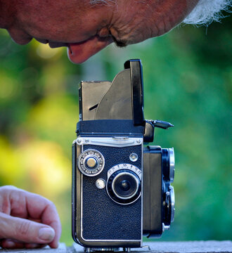 Close-up profile of a man looking into the view finder of a vintage medium format camera