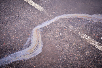 Oil, gasoline, or oil spill on wet asphalt with a parking lot and a dividing line.