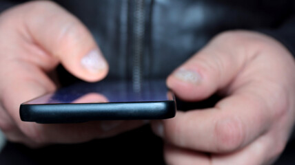 close-up of a man's hands using his smartphone