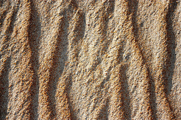 Waves on the surface of the sand, top view. The wavy surface of coastal sand. The structure of waves on sea sand.