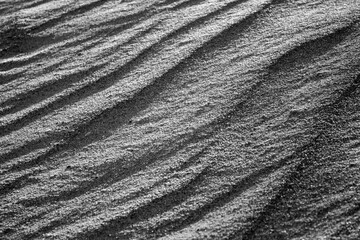Waves on the surface of the sand, top view. The wavy surface of coastal sand. The structure of waves on sea sand.