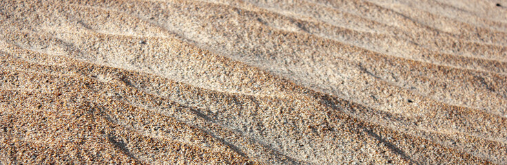 Waves on the surface of the sand, top view. The wavy surface of coastal sand. The structure of waves on sea sand.