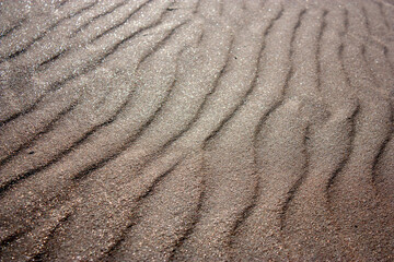 Waves on the surface of the sand, top view. The wavy surface of coastal sand. The structure of waves on sea sand.