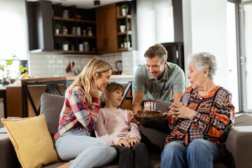 Joyous Family Celebrating Grandmothers Birthday With Cake in a Cozy Living Room