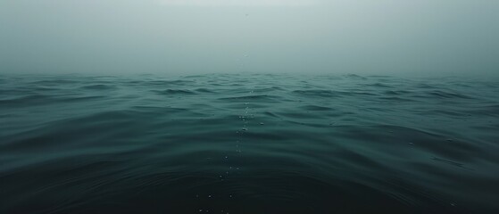 a large body of water that has some water droplets on the surface of the water and the sky in the background.