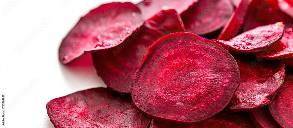 Poster a bunch of vibrant beet root chips scattered on a clean white table. the sliced beets are neatly arr