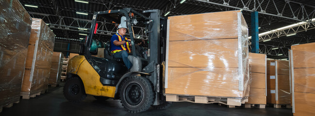 Warehouse worker workers with forklift in a warehouse. Use forklift operator moves packages....