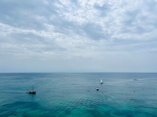 Cloudy seascape, sail boats silhouettes at the sea