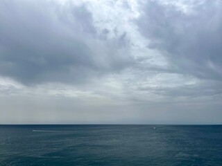 Obraz premium Cloudy seascape, sail boats silhouettes at the sea