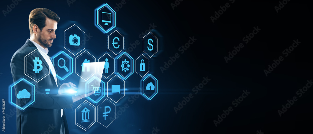 Aufkleber Attractive young european businessman using laptop with abstract hexagonal pattern hologram with various business icons on wide dark background with mock up place. Digital dashboard and data concept.