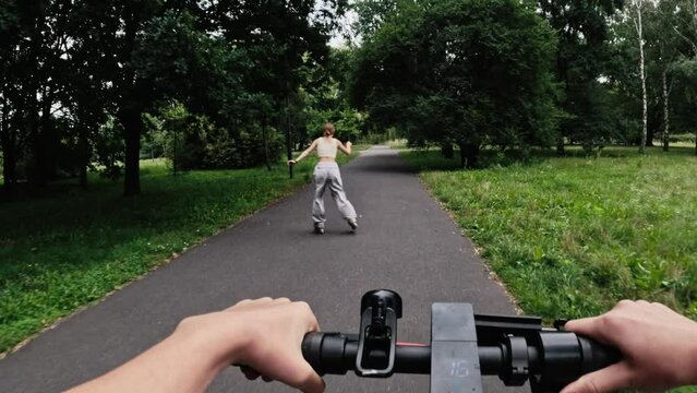 Young woman riding electric scooter with rollerscating teenager girl in park. Friends with modern vehicles enjoying outdoors activities at summer