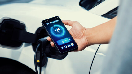 Businessman holding smartphone display battery status interface by smart EV mobile application...