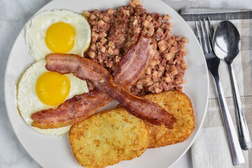 two fried eggs with  bacon and hash browns