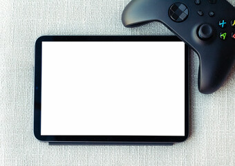 Tablet with white mockup screen and a gamer controller. Watching video or playing mobile game...