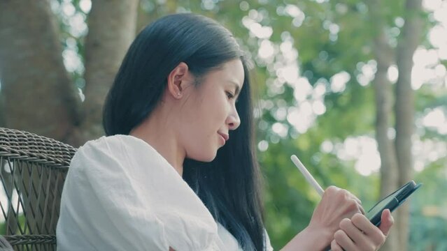 Young beautiful asian woman holding digital tablet in hands using smart pen writing down thoughts taking short note, online work remotely, thinking of new creative ideas, imagine make it real