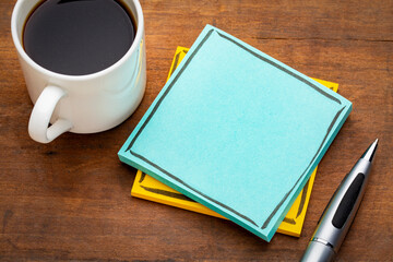 blue, blank reminder note on a grunge wooden table with a cup of espresso coffee