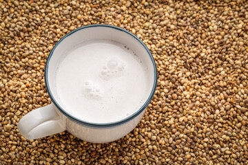 cup of hemp milk against dry hemp seed background